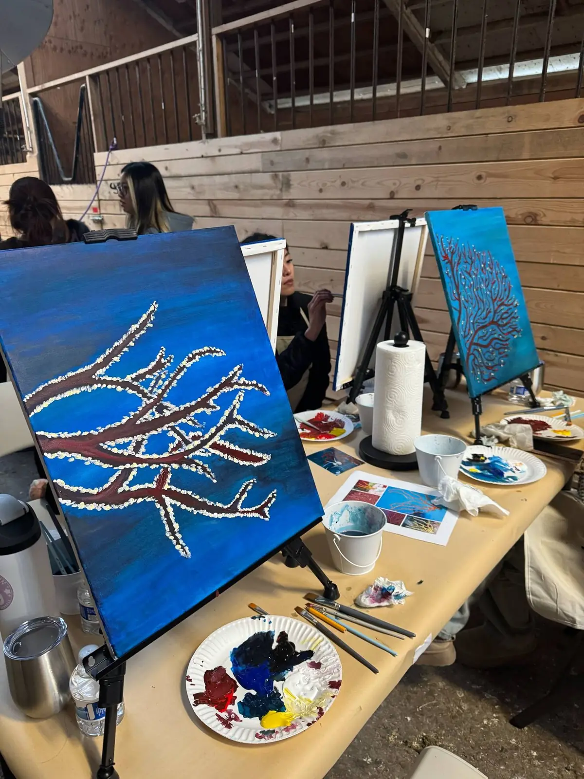 Coral and ocean paintings drying on easels