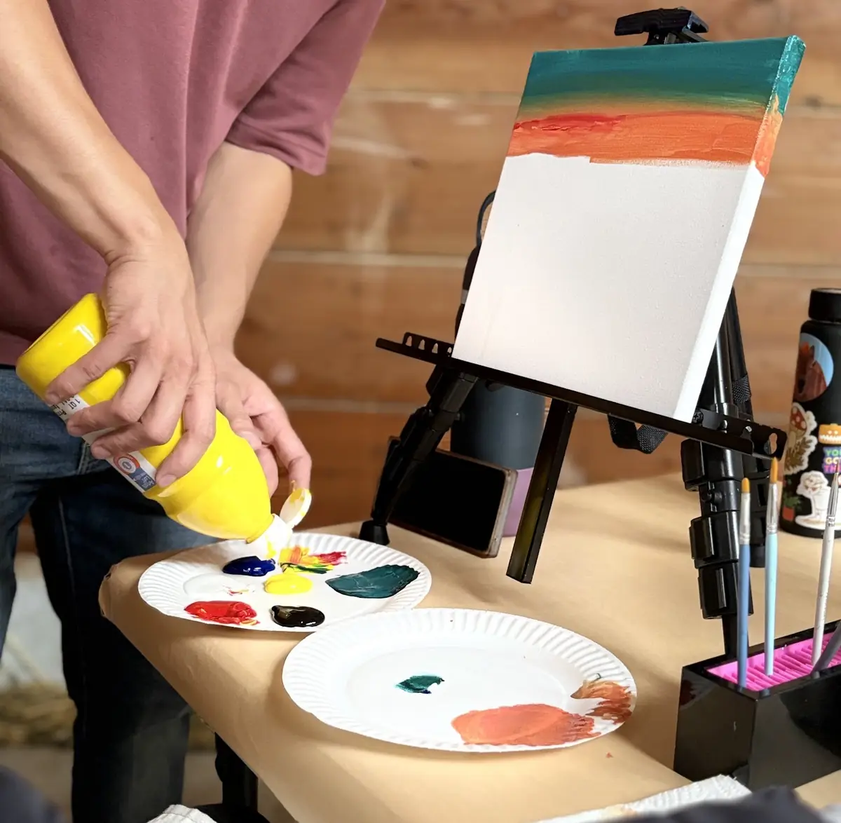 Yellow paint being squeezed onto a palette next to a canvas
