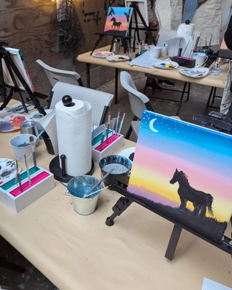 Finished sunset paintings of a horse on easels along the table